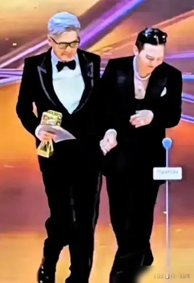 周润发在韩国颁奖礼上小碎步上台，顺手把旁边走得慢半拍的大哥胳膊一捞，俩人像连体婴
