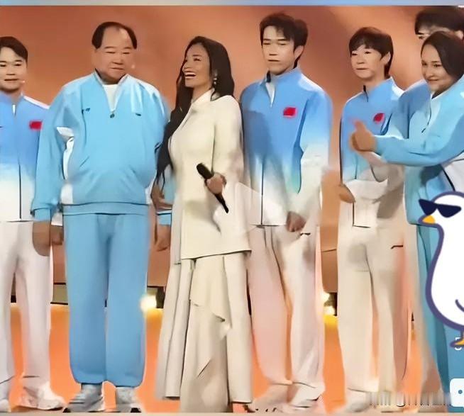 韦韦站在老中青三代运动员的中间，还是那么潇洒靓丽。她侧身面向一位老运动员，表示她