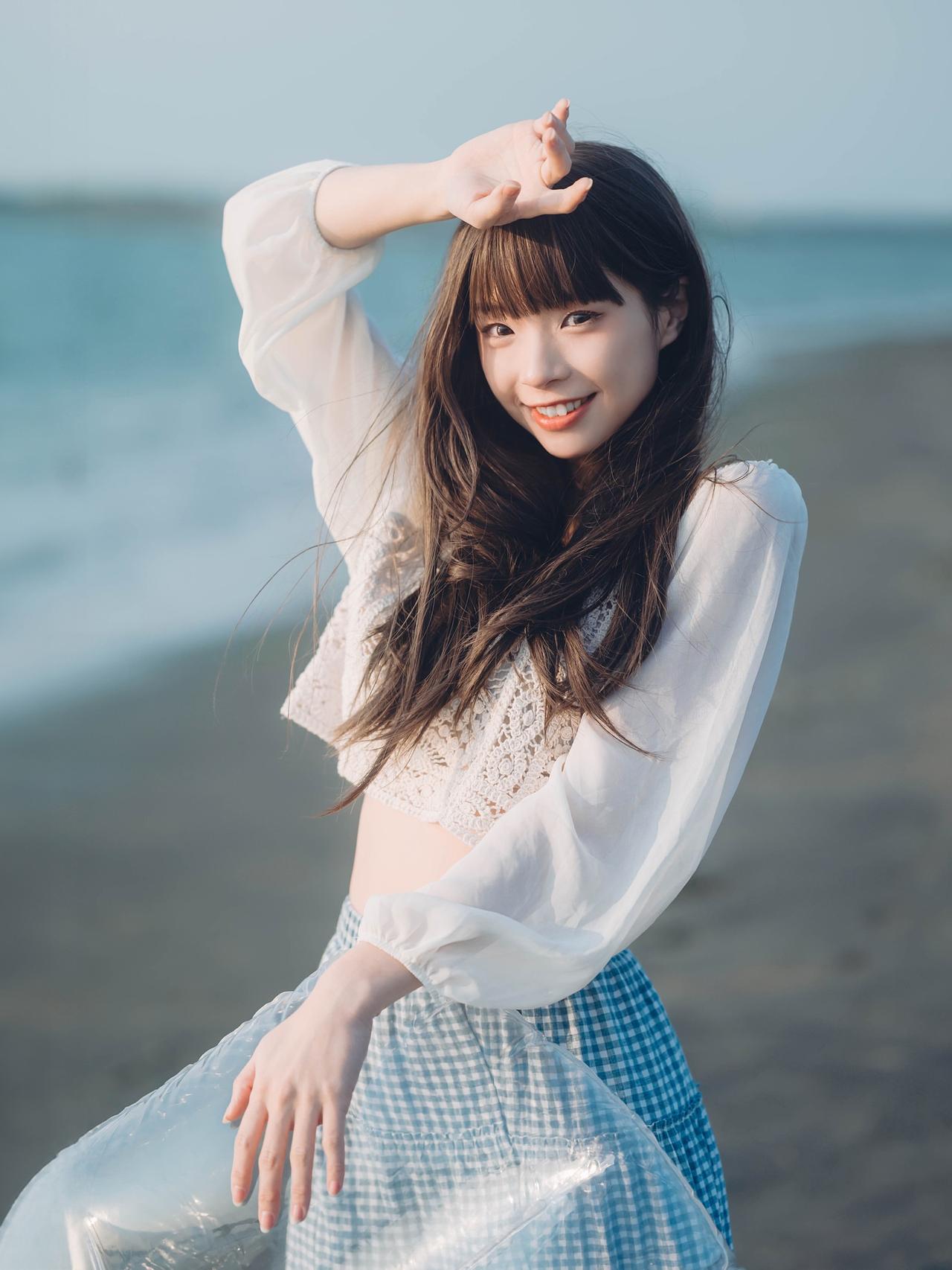 海边少女，温柔微笑，海风吹拂，白色蕾丝衫，蓝色格子裙，阳光明媚，幸福时光。