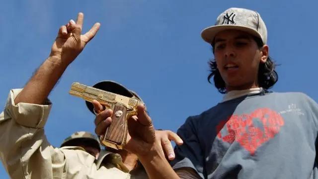 下图是利比亚青年乌雷比，拍各种视频和照片炫耀自己刚刚从卡扎菲那里缴获的黄金手枪，