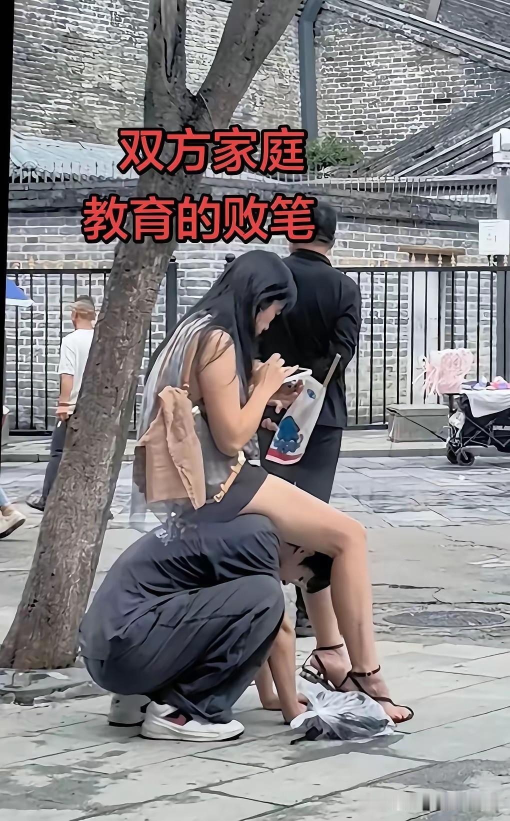街头这一幕，引来不少网友议论。
男生趴在地上，低头给女生当凳子，姿态放得很低，看