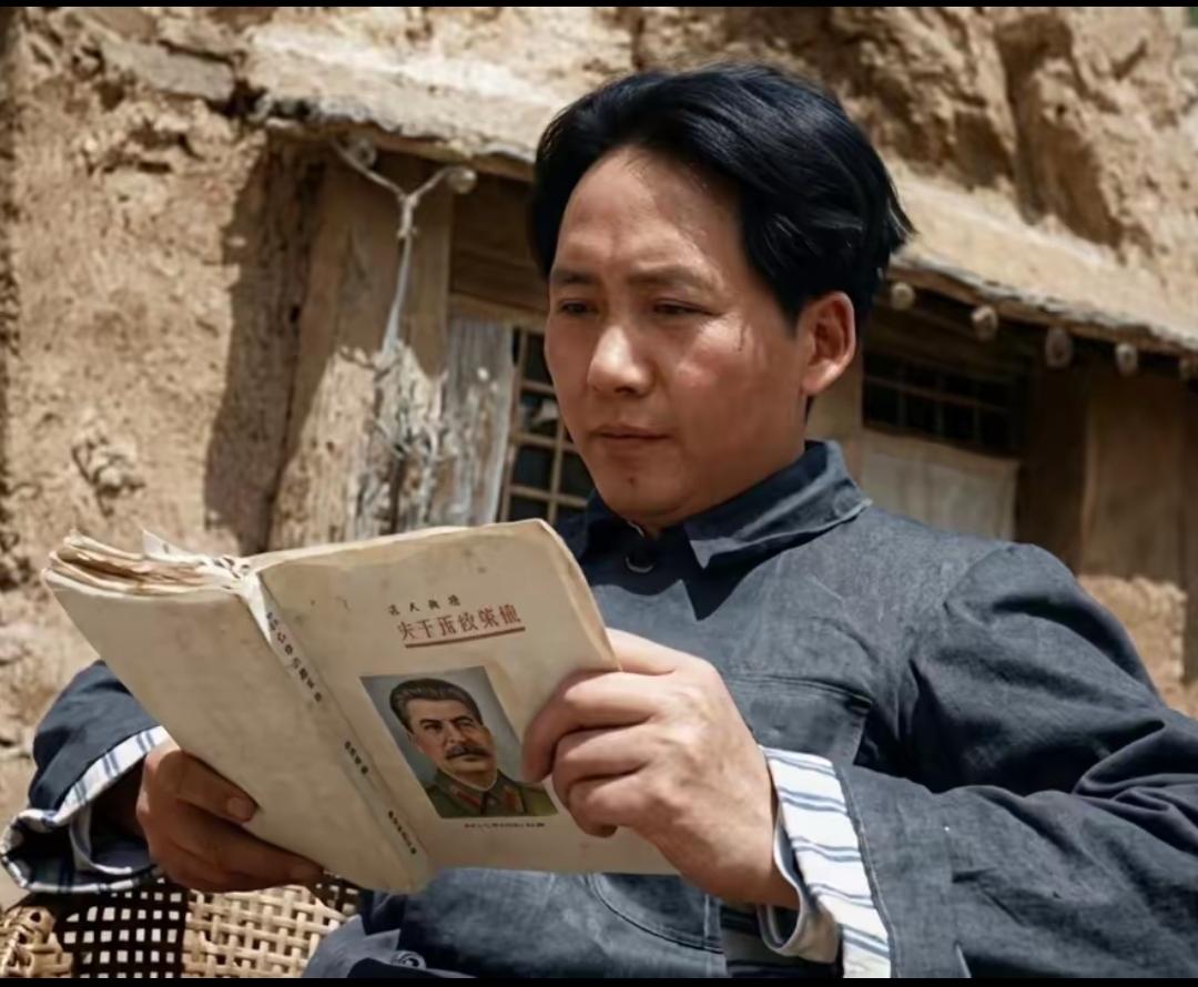 在延安时期，毛主席在破旧的窑洞外，坐在藤椅上正在专心的看书《关于民族政策》，是斯