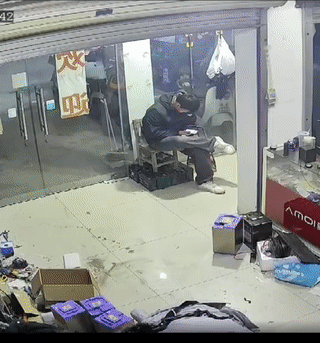 河南南阳一男子正坐在自家店里玩手机。
这时突然从外面冲进来一名骑车男子，竟然直接