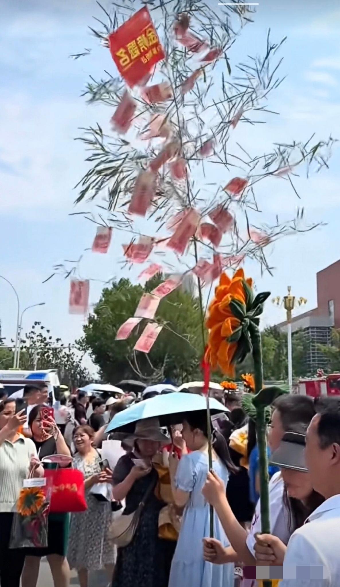 高考结束，校门口的一幕直接看呆路人：一位家长举着一根柳枝，枝桠上挂满了百元大钞，