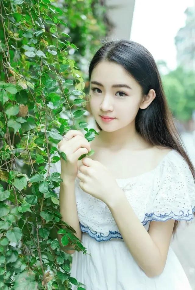 一个女孩在绿叶前微笑。