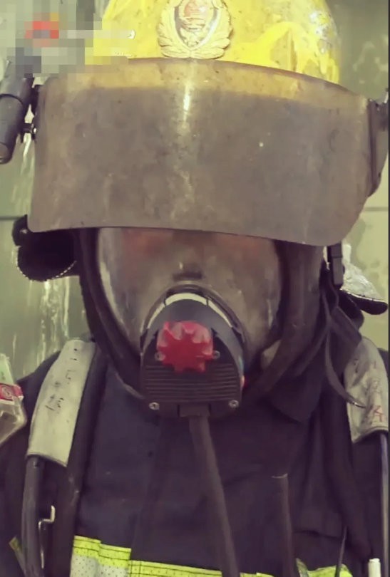 这是一位刚刚结束灭火的消防小哥哥，摘掉覆盖灰烬的头盔露出帅气的笑容，为勇敢乐观的
