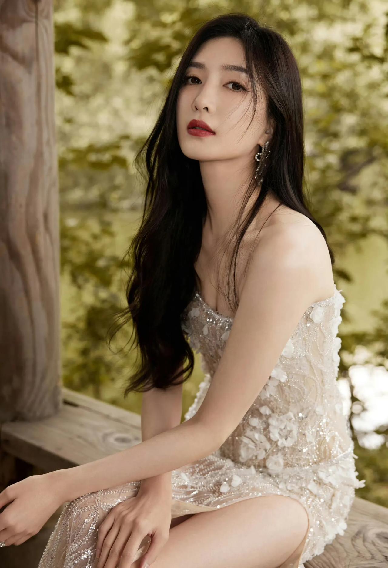 照片中她画着精致的妆容，一头柔顺飘逸的长发，尽显东方女性的温婉柔美。略微抬头温柔