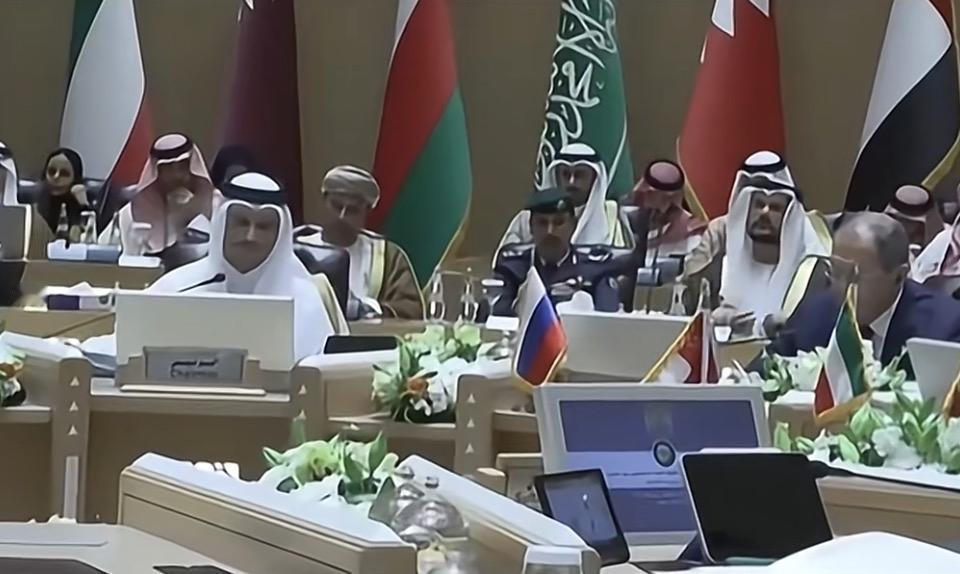 一群人在会议室里开会，桌上摆着国旗和电脑。