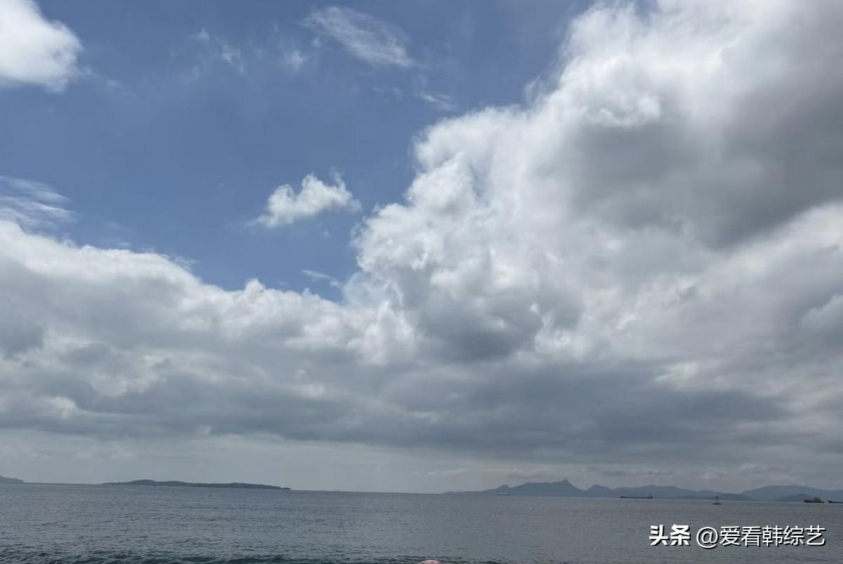 秋日生活打卡季辽阔海面泛着淡淡波光，大朵云团漫过澄澈蓝天。远处山峦朦胧伫立，海面