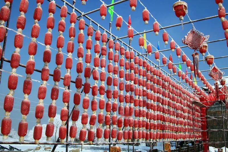 红灯高挂大门前，
联对迎新岁月绵。
石碾鸡群成回忆，
狮立门前威严添。