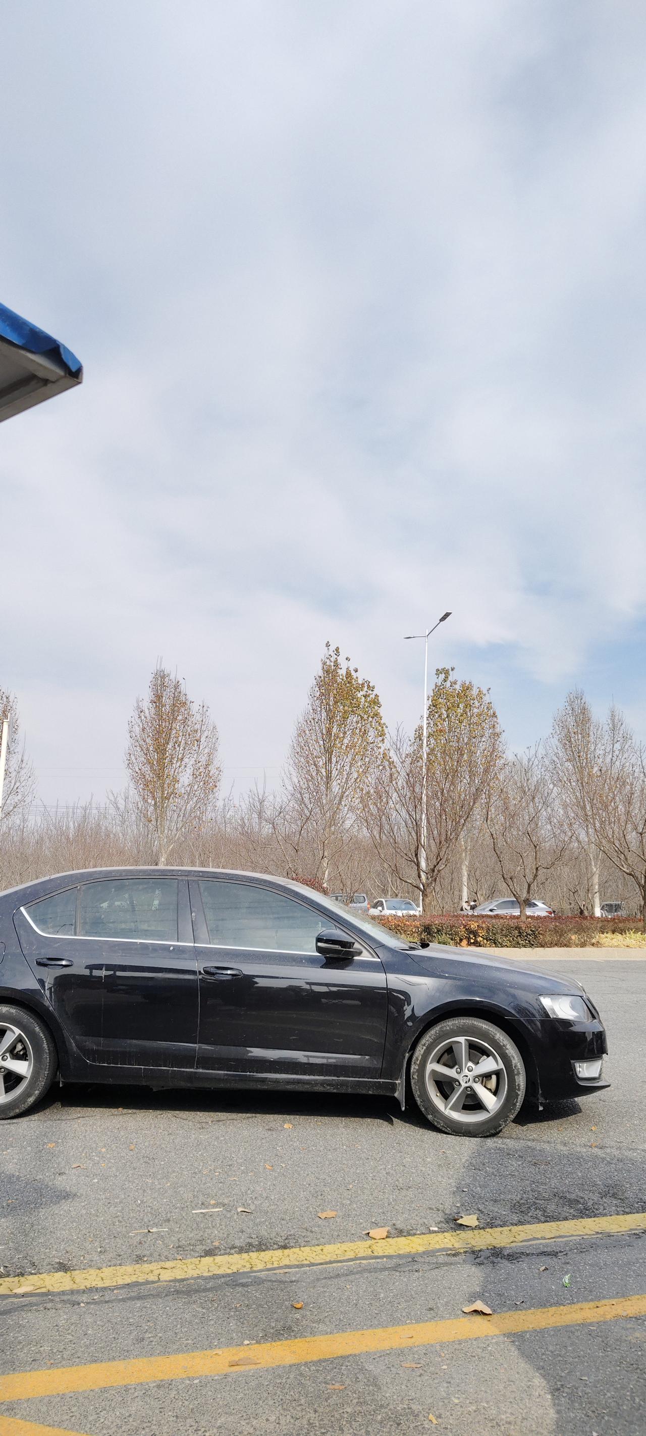 周末出门，在停车场看到一辆黑色的斯柯达明锐停在黄线旁，车身落了些灰尘，看得出来是