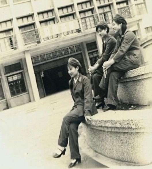这是一张上世纪六、七十年代的老照片。照片上三个女兵呈品字形坐在花坛上拍摄了这张合
