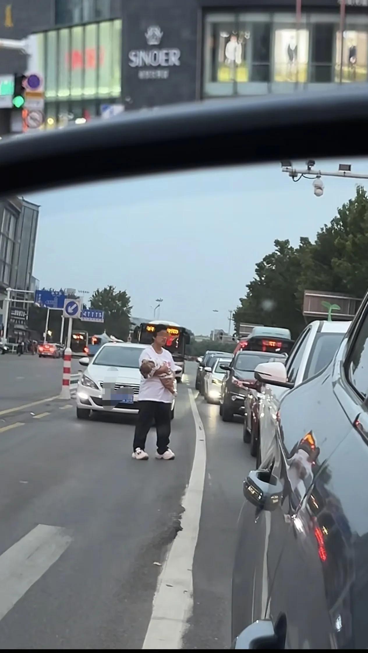 女子怀抱婴儿站在车水马龙的路中央，拦截一开车男子并当街大喊：“你欺骗了我的感情，