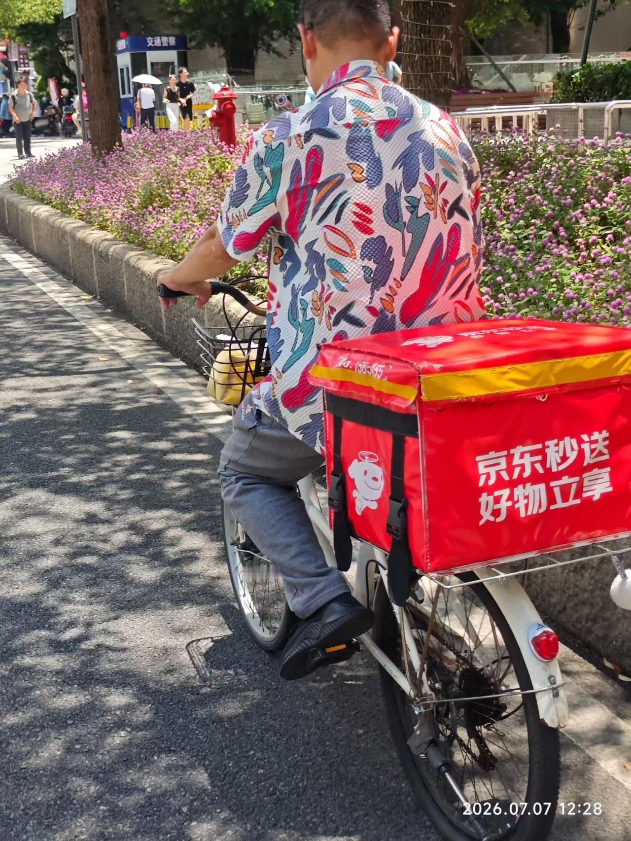 盛夏福州东街口，烈日当头，街边繁花盛放。花衬衫骑手骑着老式自行车慢行，车尾鲜红的