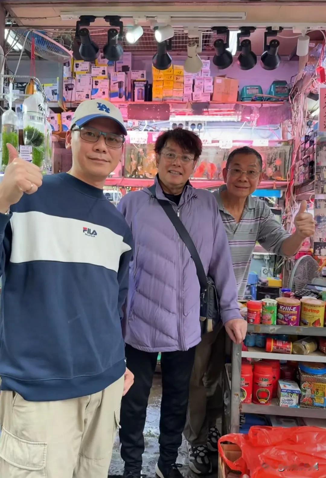 谭咏麟现身香港一家卖鱼店，为过年添景买观赏鱼。
他穿着一件紫色的羽绒服，黑色裤子
