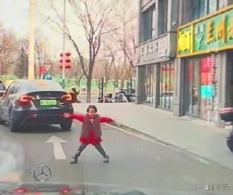 2月14日，北京，一小女孩调皮地站在路中间拦车，吓得司机不敢轻举妄动，停车原地等
