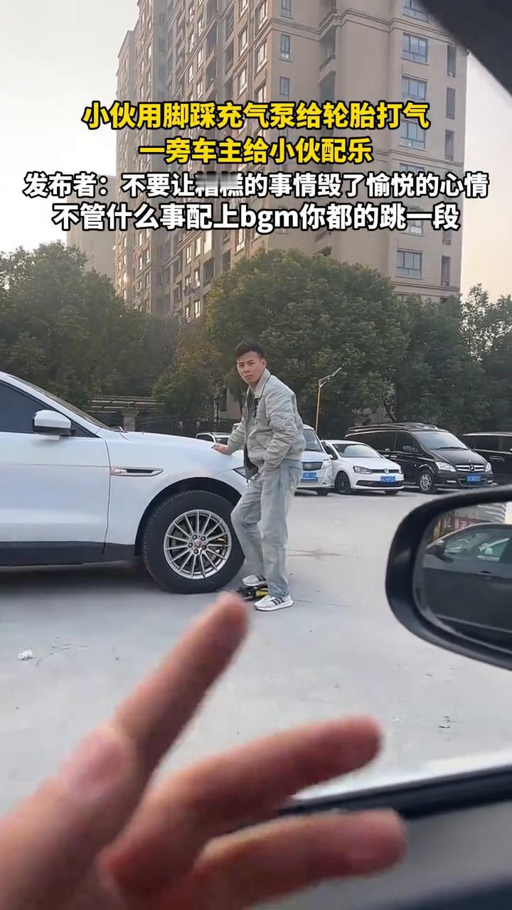 小伙用脚踩充气泵给轮胎打气，一旁车主给小伙配乐。
发布者：不要让糟糕的事情毁了愉