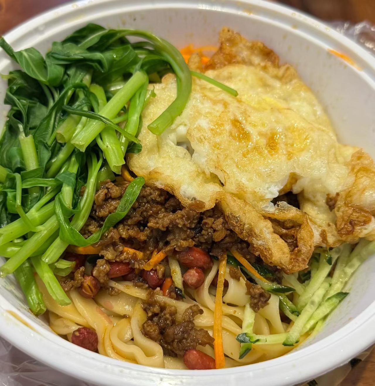 一碗丰富的牛肉面，配煎蛋和蔬菜。