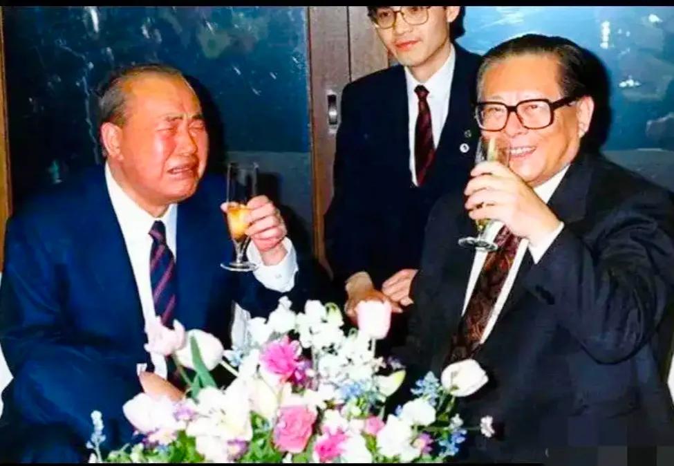 这张照片拍摄于1992年，展现了日本前首相田中角荣端起酒杯的情景。他的表情有些苦