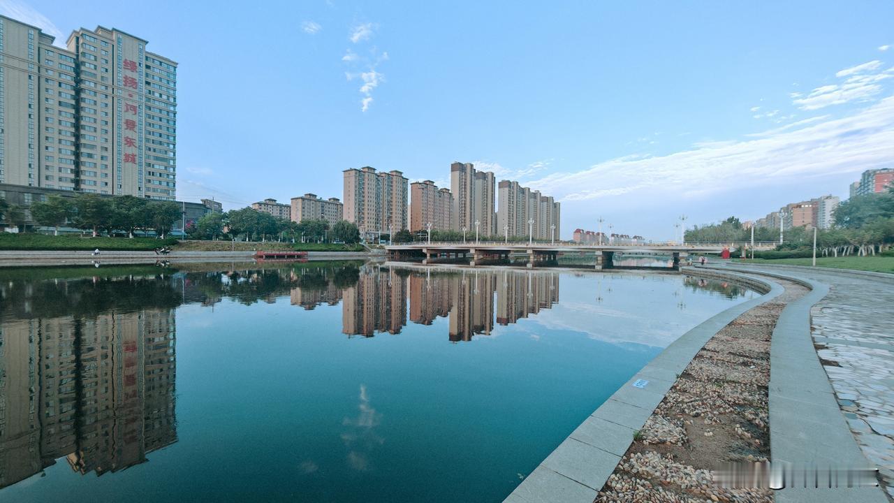 《七律·晨河倒影》
抱龙河畔晓光微，水镜初磨映翠微。
数栋楼台浮浪底，半城烟树入