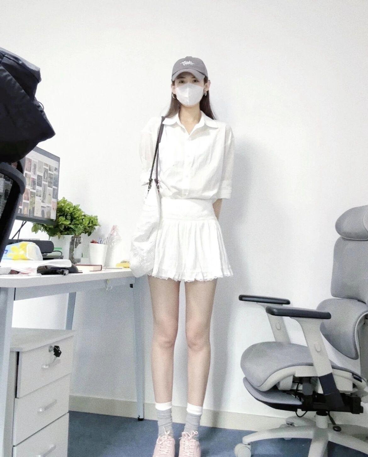 穿白色衬衫和短裙的女孩站在办公桌前。