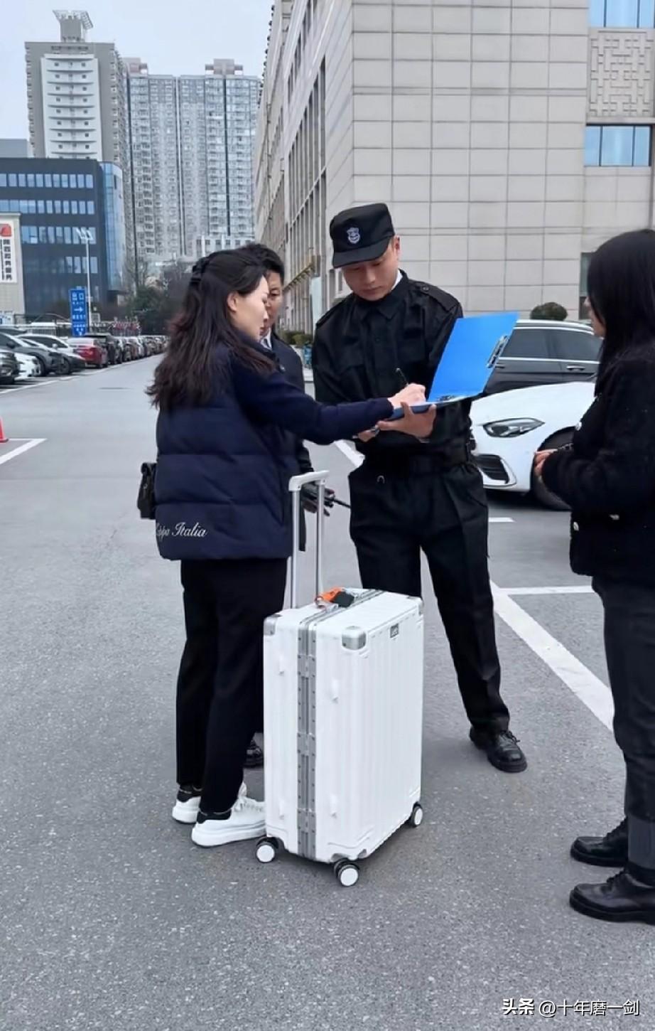 一女士等待乘坐高铁，手拿身份证，拉着箱子，她打电话时，被一个女骗子用手机拍到了身