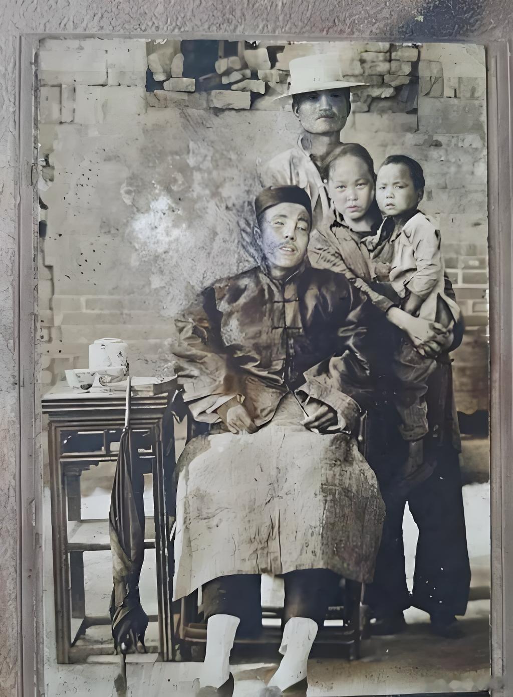 1928年，陕西。民国，渭南农村的全家福。衣着整齐但身躯僵硬的男子坐椅子上。他双