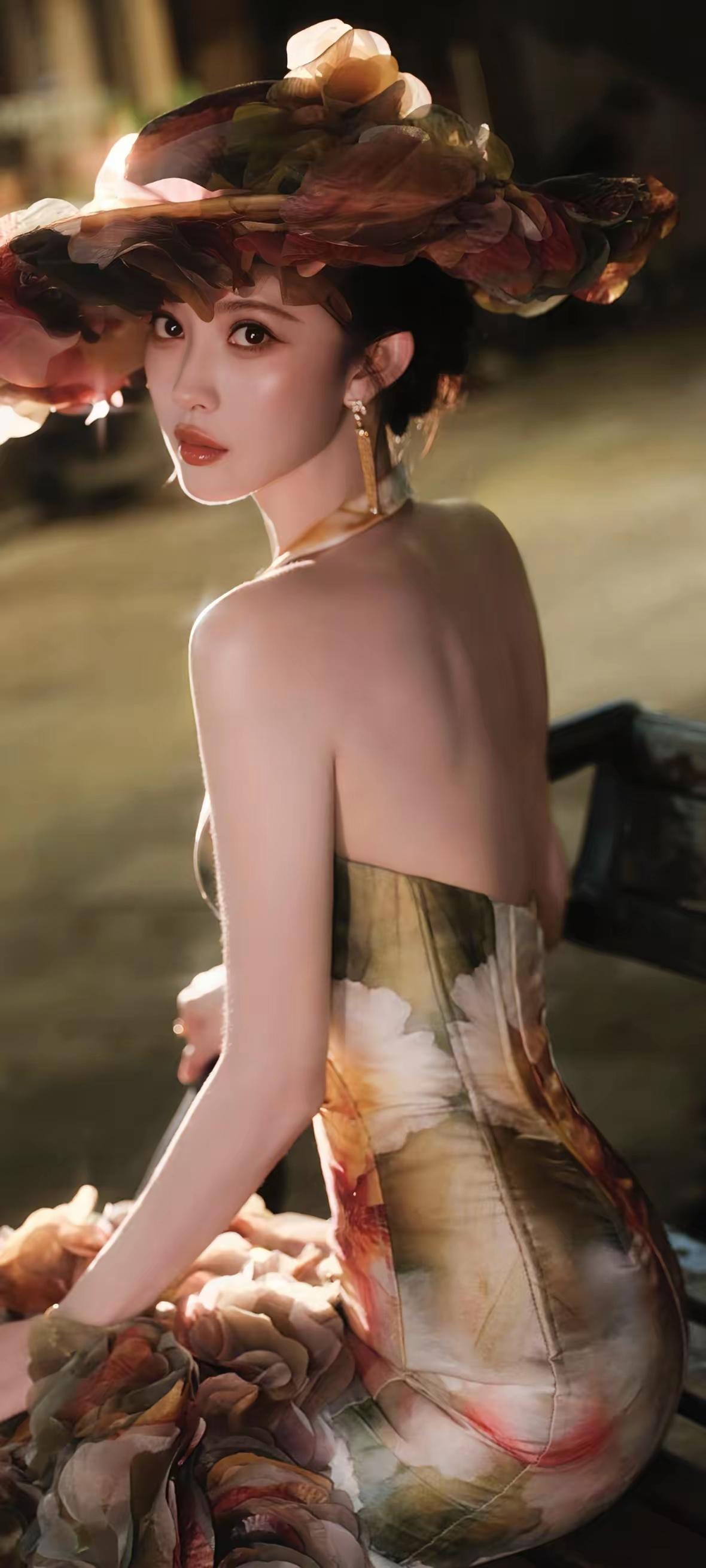 孟子义，暖光漫过复古廊间，油画感晕染的挂脖鱼尾裙勾勒出玲珑曲线，层叠花帽与立体裙