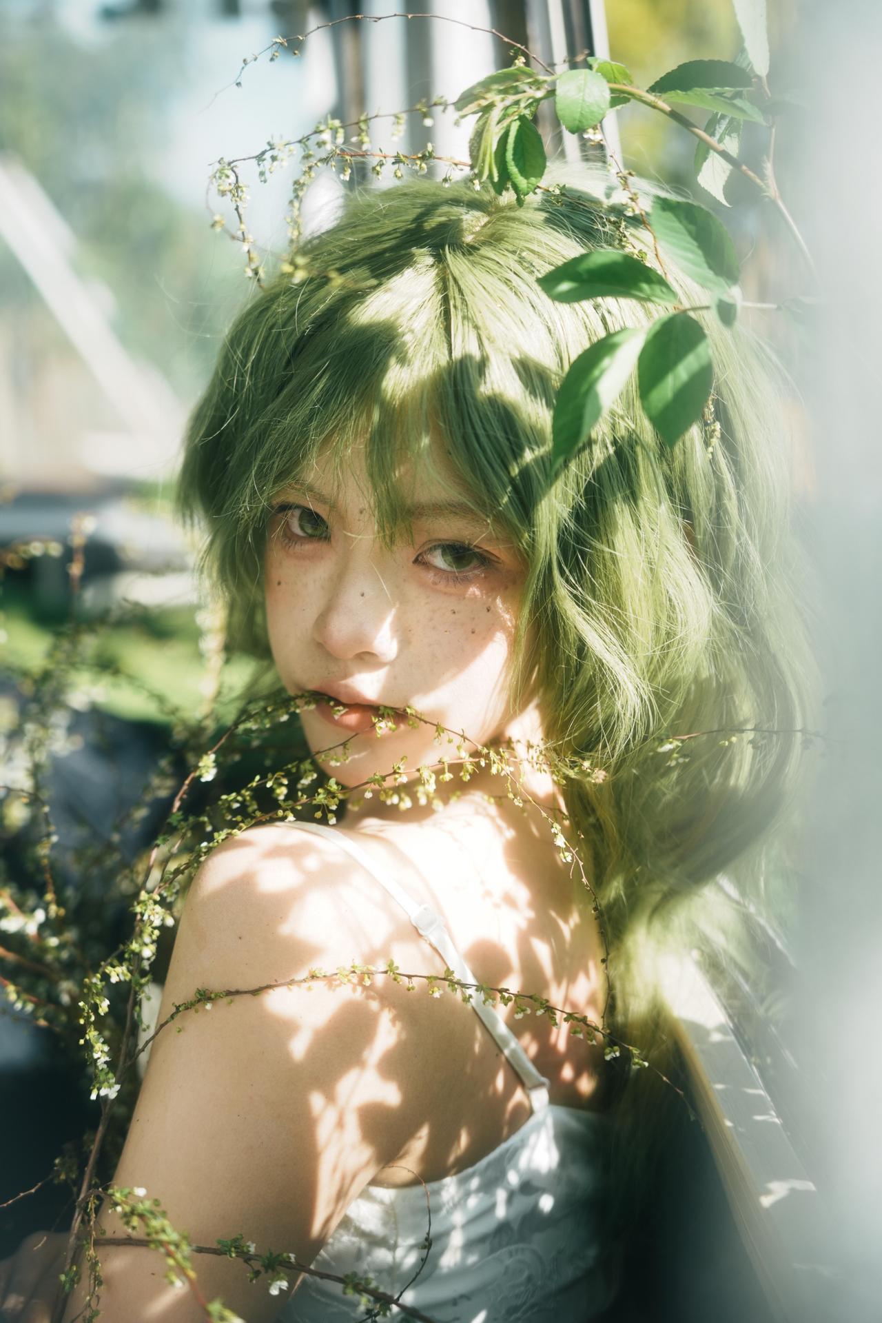 作品的构图极具巧思，前景的雪柳枝桠形成了天然的画框，将人物的面部置于画面中心，实