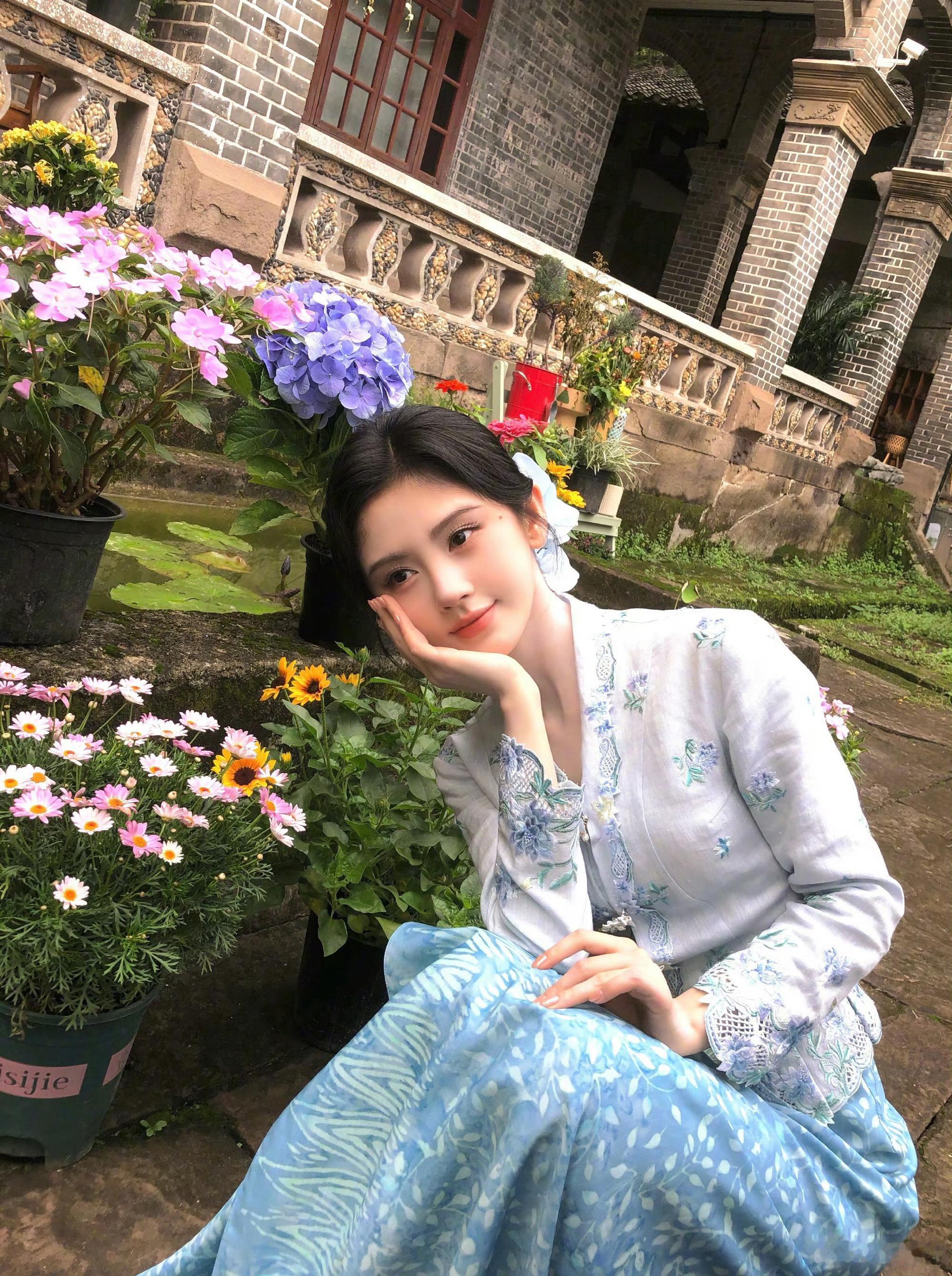鞠婧祎这身小娘惹造型好有味道，旧宅院、繁花相伴，温婉柔和，像从老故事里走出来的姑