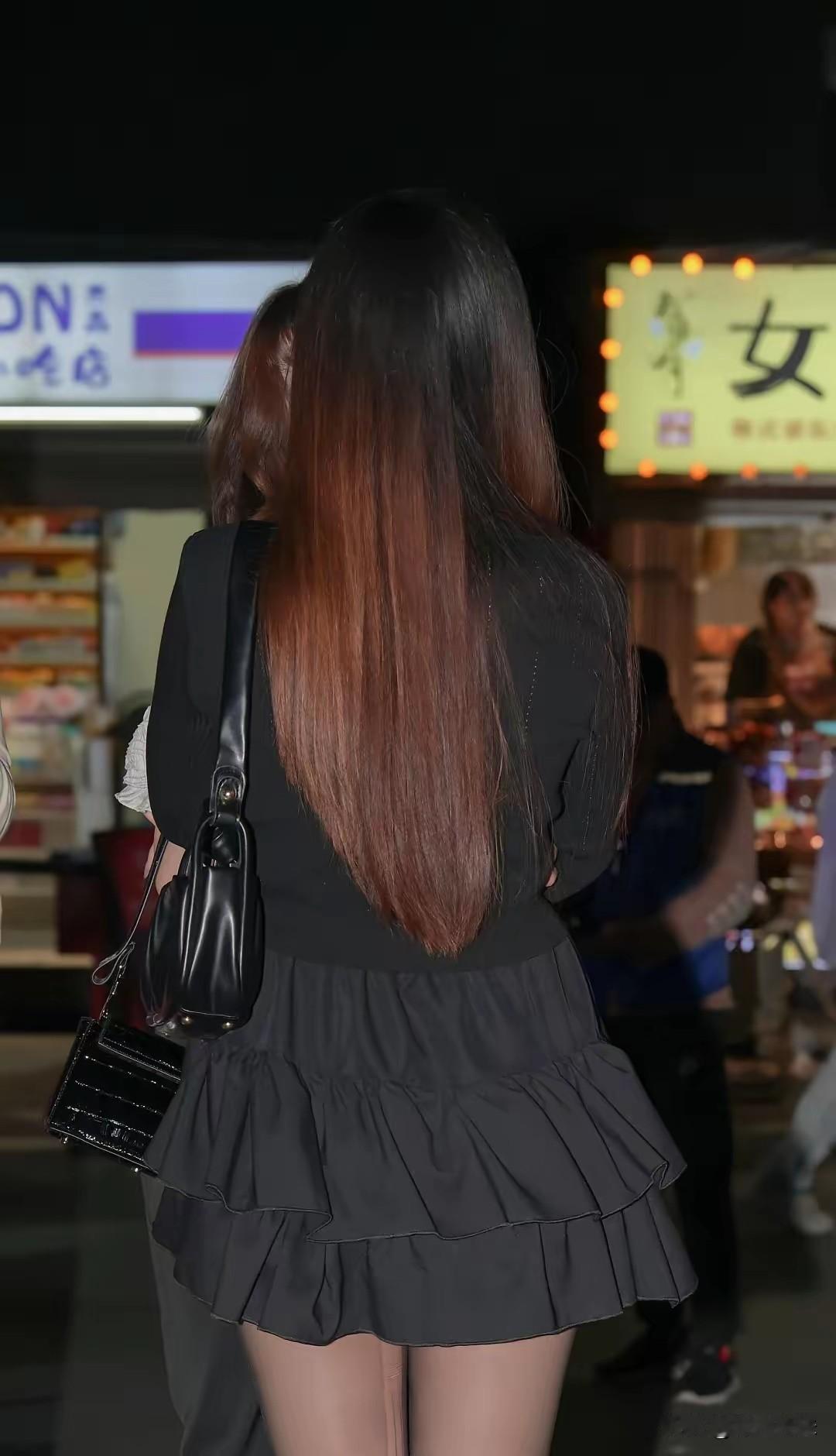 夜晚的街头，长发飘逸，黑色裙摆随步伐摇曳。