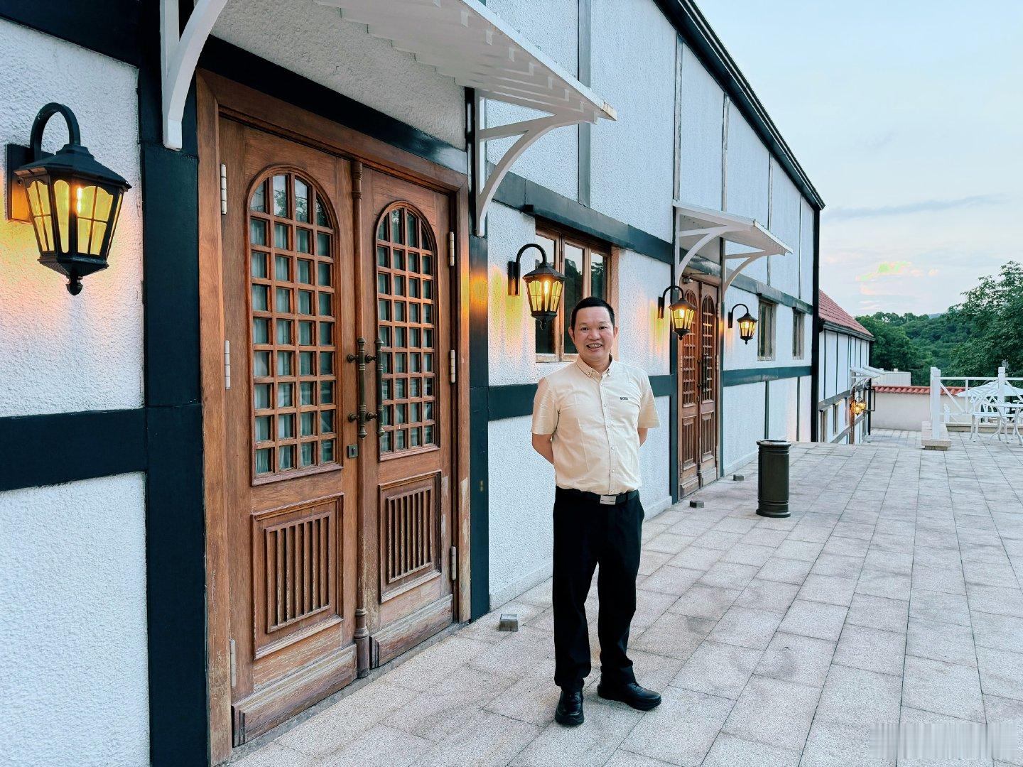 暮色漫过白墙黑木的欧式小屋，暖黄壁灯次第亮起，氛围感瞬间拉满。木质拱格门搭配错落