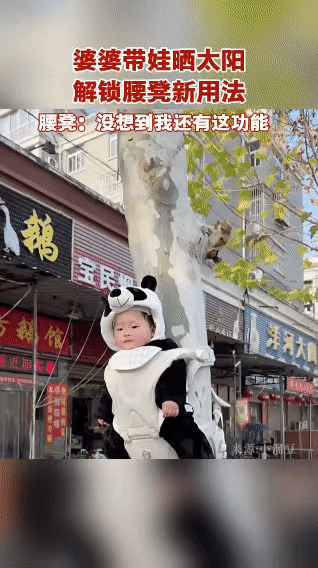 婆婆带娃晒太阳，直接把穿熊猫服的宝宝“挂”在树干上，腰凳秒变“树挂神器”，连娃都