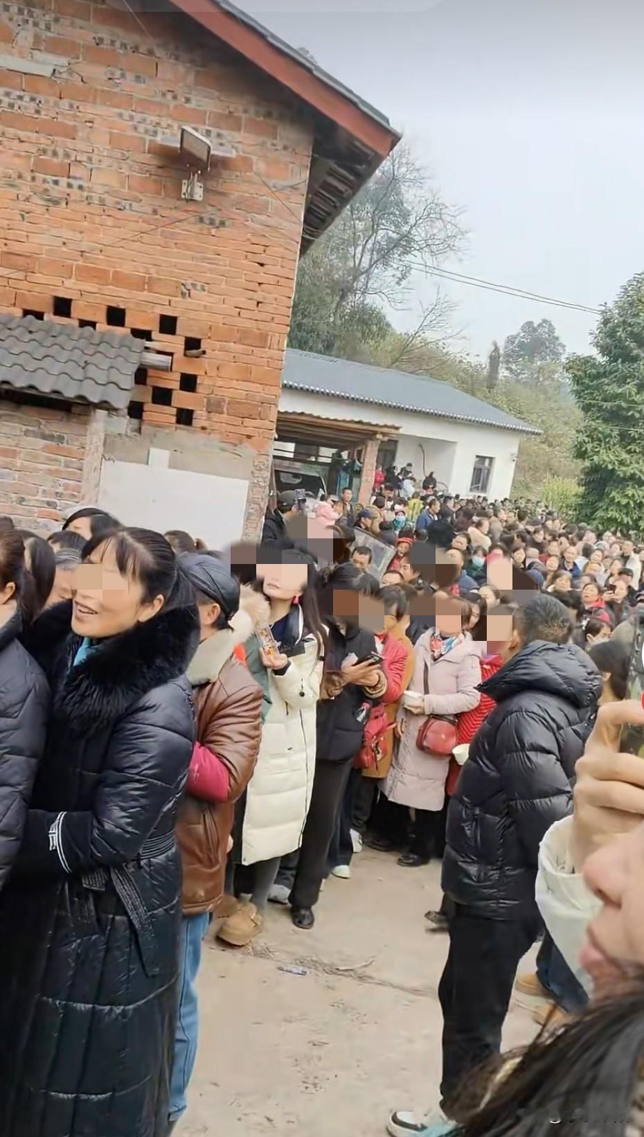 下图又是某地一效仿重庆合川杀猪宴的现场，可以看到现场聚集的人很多，手里拿着一次性