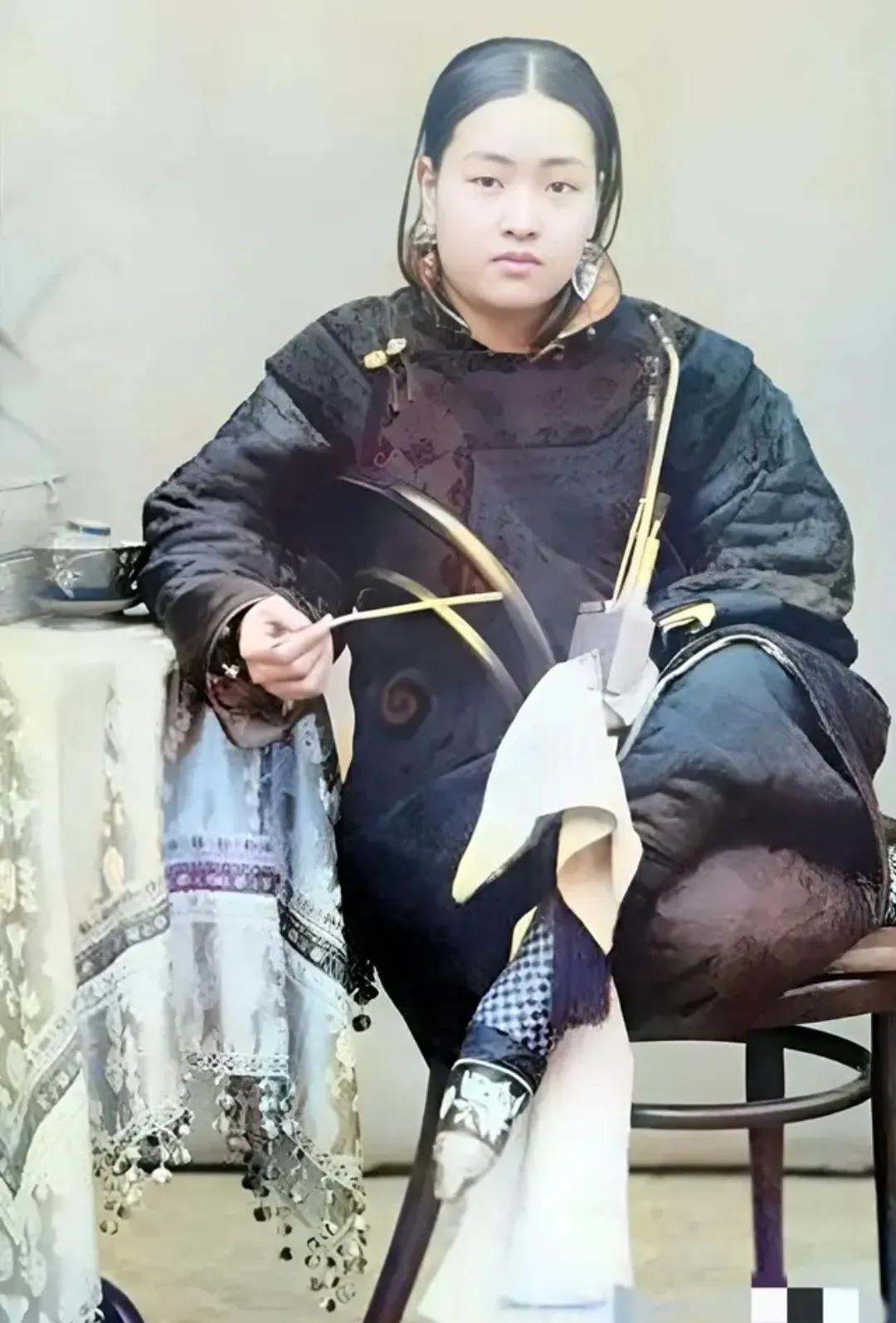 1900年，天津，一位长相富态的女子，翘着二郎腿，正坐在家中拍照。仔细看她的五官