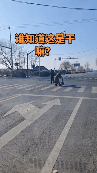 这是在干嘛呢？
网友开车在公路上看到非常诡异的一幕？
有两位老人站在十字路口手拿