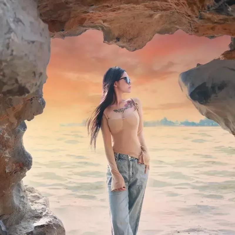 海边的岩石洞里，一位时尚女孩眺望远方，海天一色，美不胜收！海边度假女孩 海边游玩