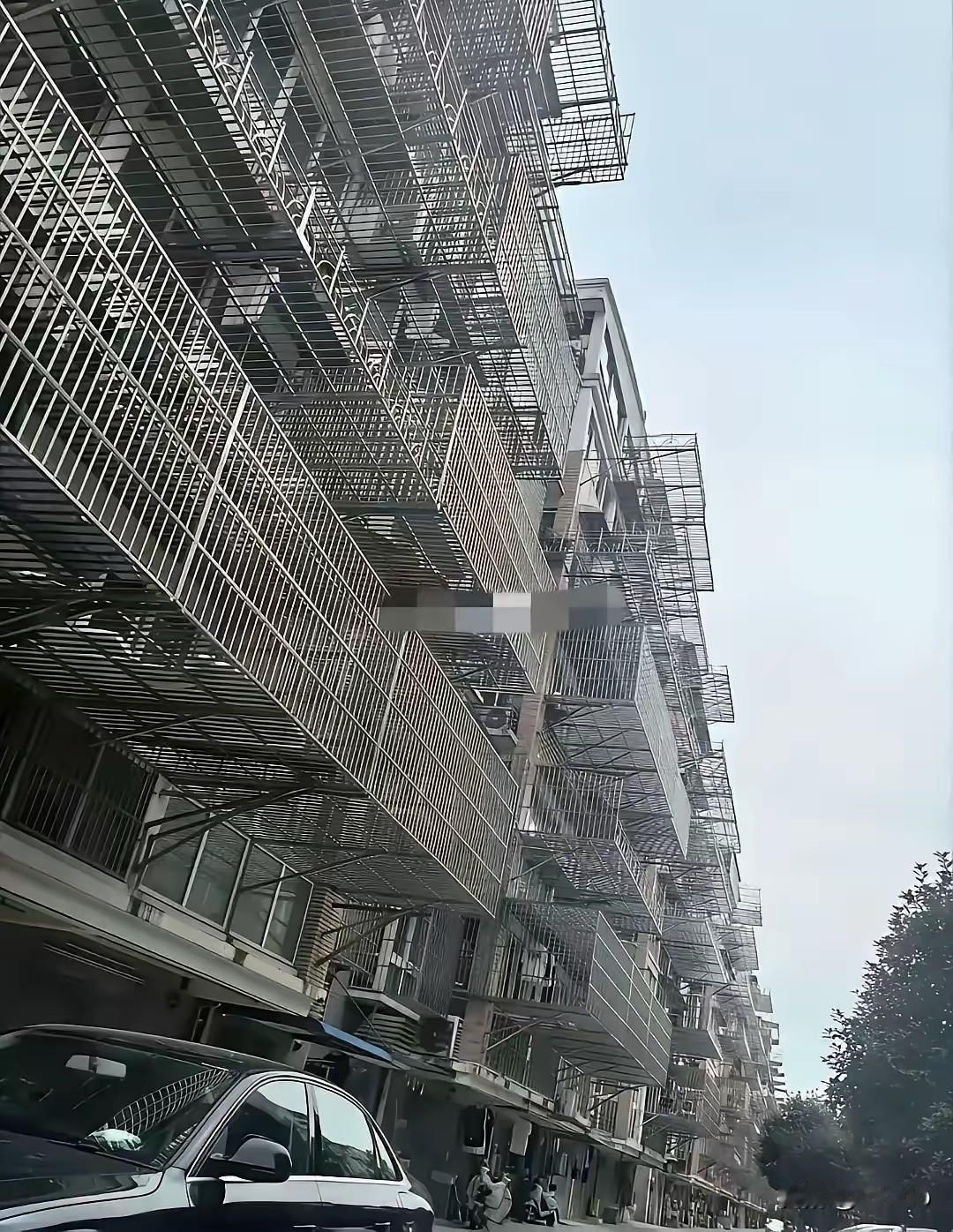 一栋居民楼的外墙，渐渐被各种加建的铁窗、棚屋包裹，原本的样貌几乎消失。这些附加结