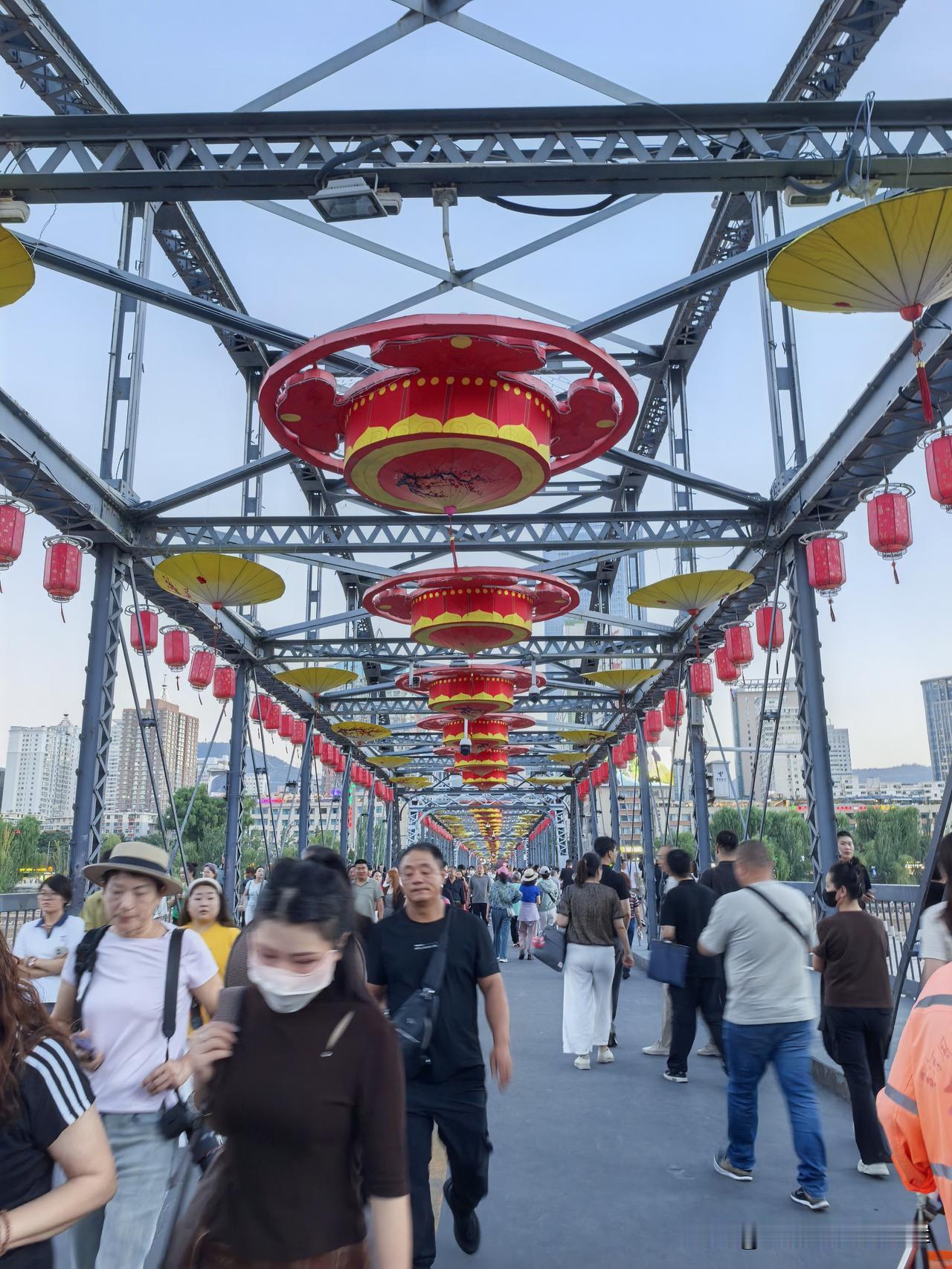 这座百年铁桥始建于清末，横跨滔滔黄河。

夜晚灯光不断变换色彩，光影洒在河面波光