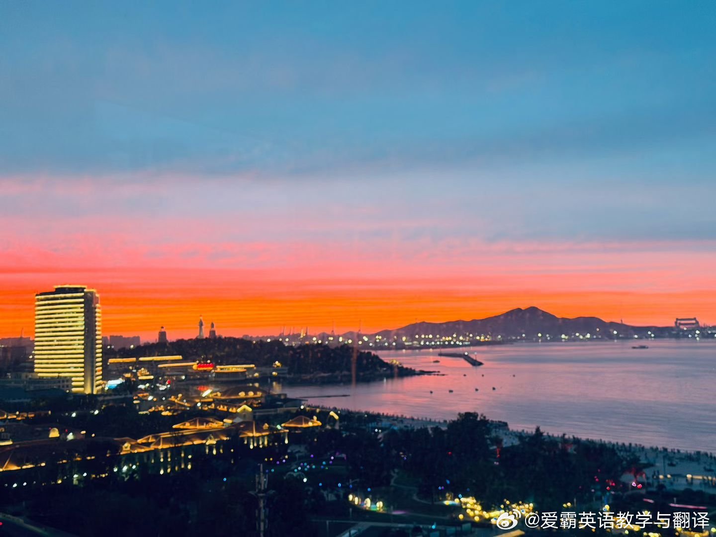 落日把天际染成绯红晚霞，霞光漫过海面，整片海湾都浸在温柔暖红里，暮色静谧浪漫……