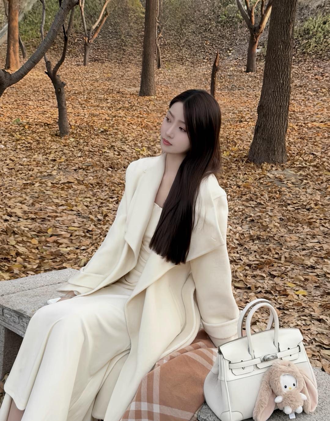 秋日暖阳下，优雅的白色套装与毛绒小兔子包，尽显温柔与时尚。