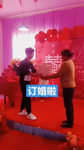 订婚现场，男孩将一束鲜花献给了旁边的一名中年女子。
刚开始我还以为这名中年女子是