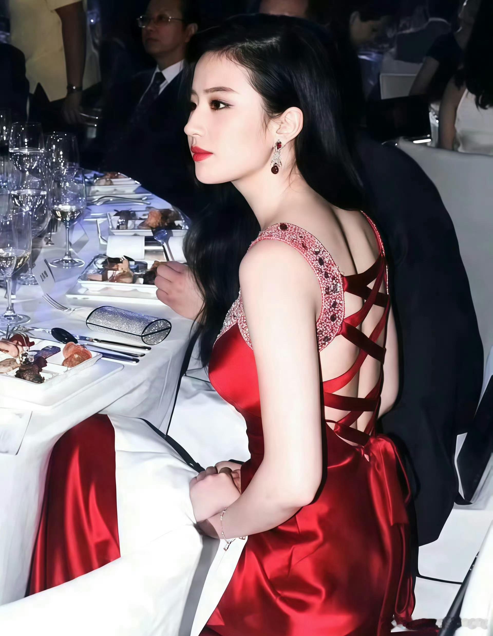 刘亦菲身着立体玫瑰礼裙，抹胸设计搭配层层叠叠的红色花瓣，肩部亮钻点缀奢华感十足，