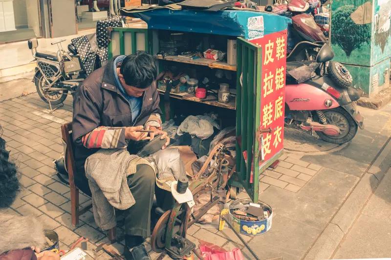 街头补鞋匠
叮当声里一凡人，
静守街边度冬春。
针线缝合鞋底洞，
只为三餐觅文银