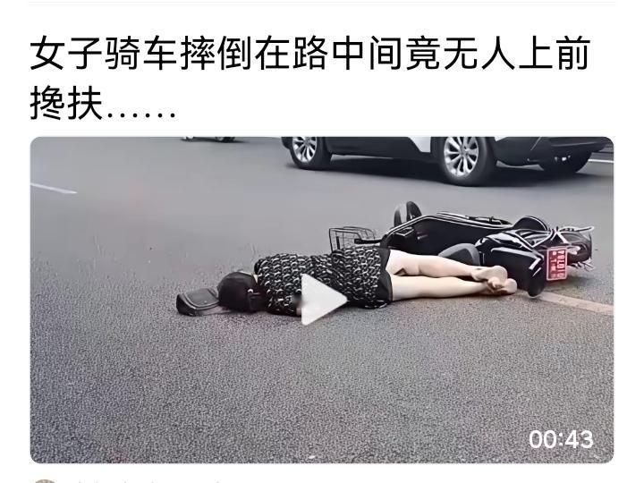 女子骑电动车摔倒在马路中央，电动车压在身上，路过的车辆和行人却纷纷绕行，无人上前