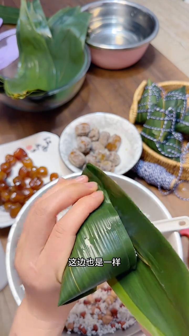 四角粽子包法。
·在上1/3这个位置折一个直角，左手大拇指摁住直角的边，右手把叶