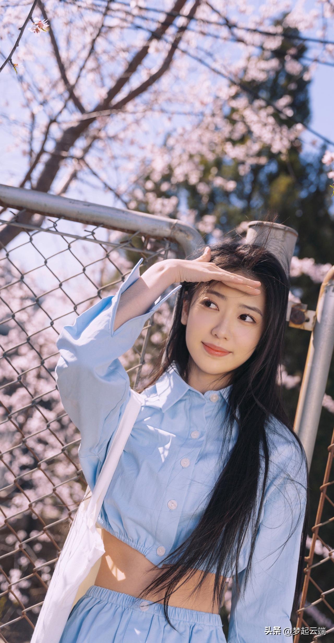 樱花树下，少女轻抚发梢，浅笑盈盈，春日气息扑面而来。