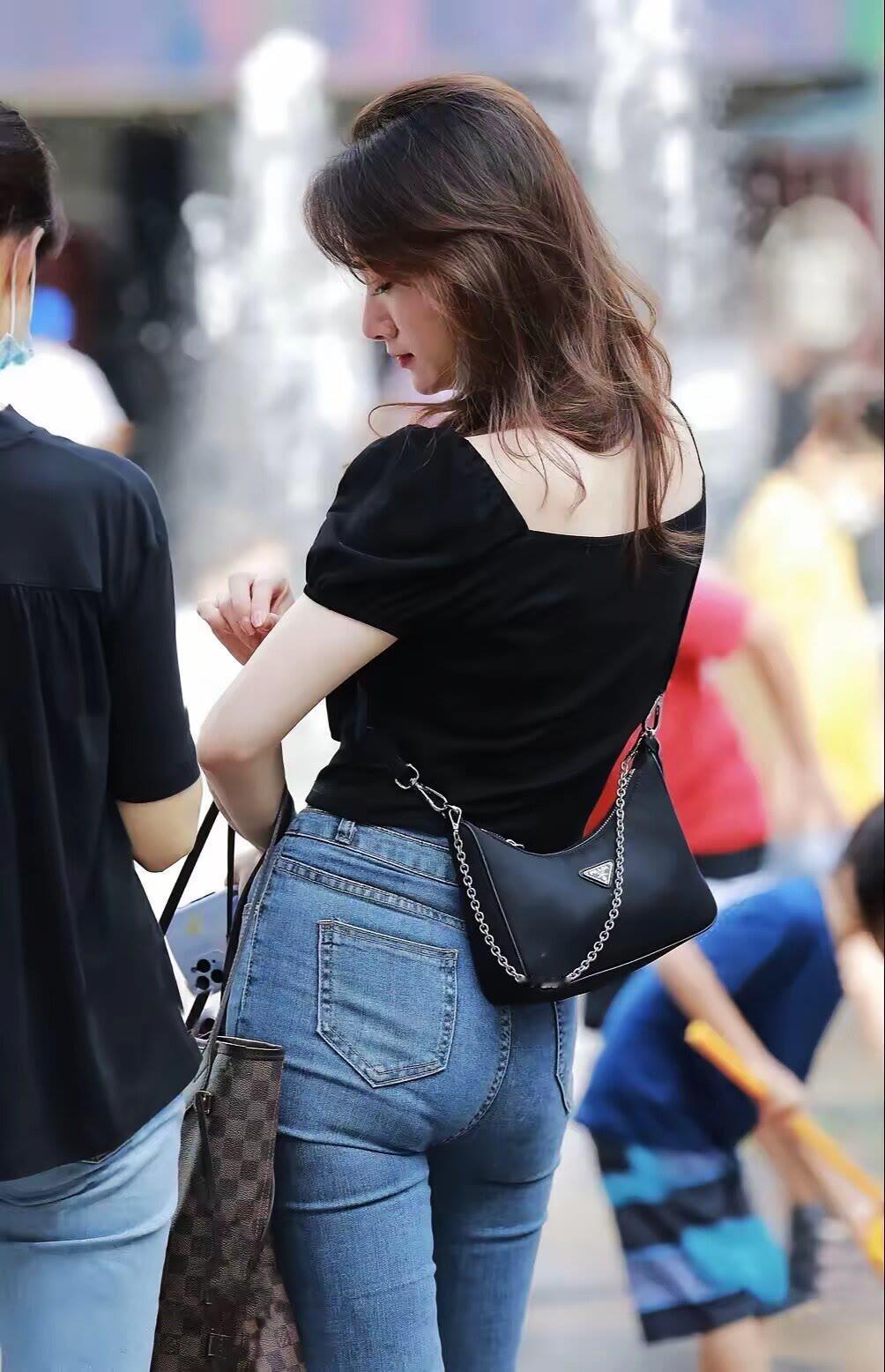 一位穿黑色上衣的女士在街上看手机。