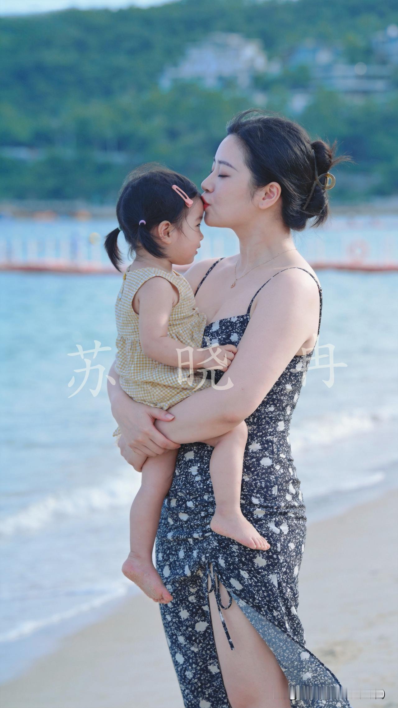 这位妈妈特别愿意表达爱，抱着孩子在海边，直接就亲孩子额头，把对孩子的喜欢明明白白