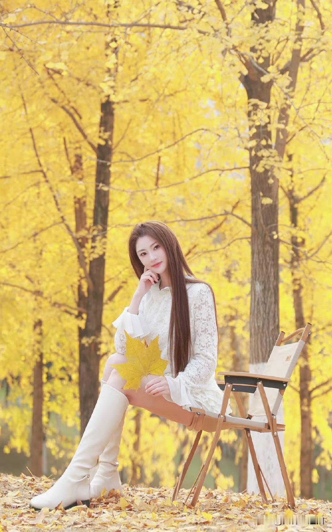 秋日暖阳下，落叶纷飞，优雅女子静坐画板旁，感受大自然的美好。
